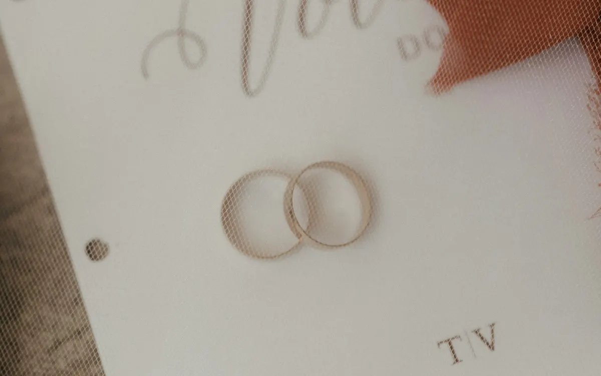 Two gold wedding rings resting on a printed vows card