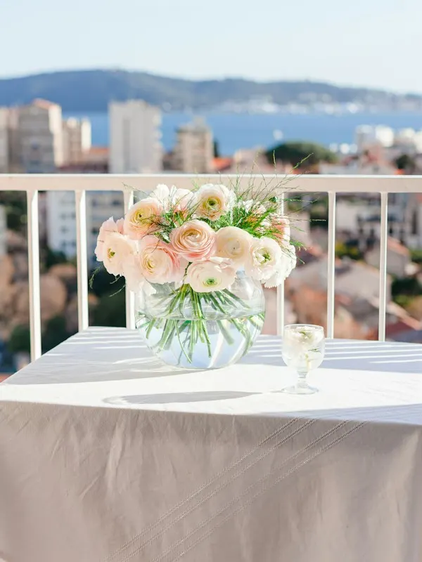 Table with a bouquet of pale roses on a hotel balcony overlooking the sea