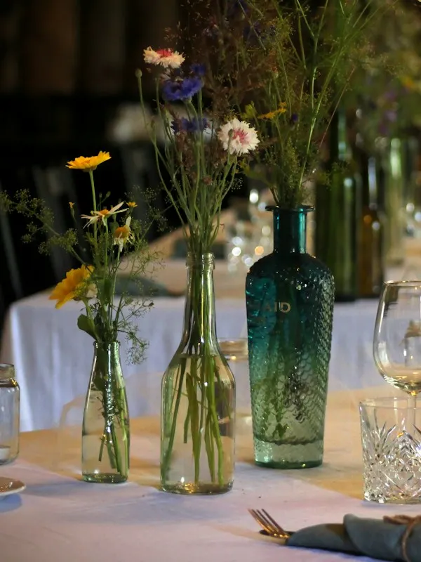 Long dinner table with wildflowers in glass bottles and a candle